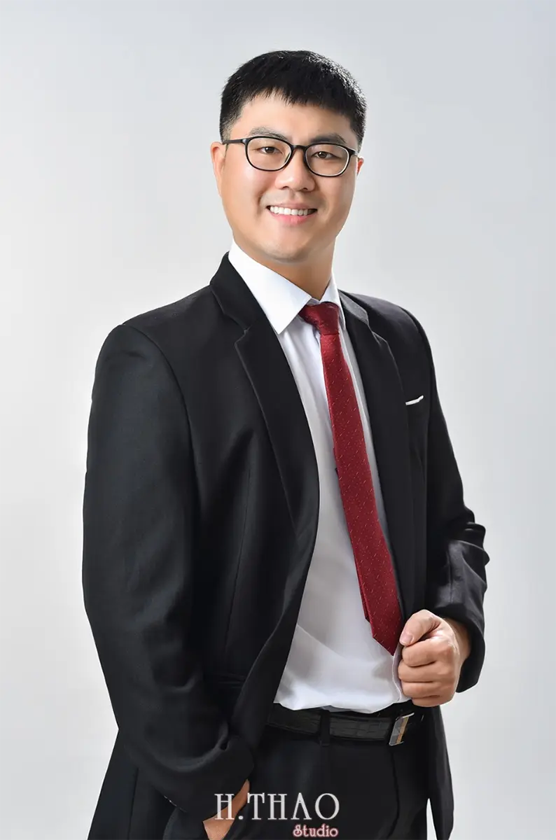 Nam doanh nhân mặc vest đen đang chụp hình profile cá nhân phông nền xám tại Hthao Studio